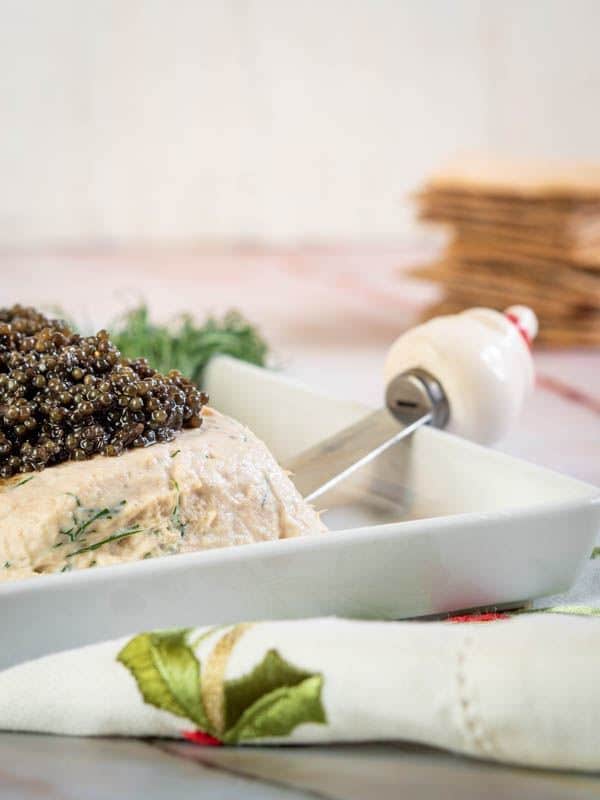 Dill salmon mousse with black caviar and crackers in the background.