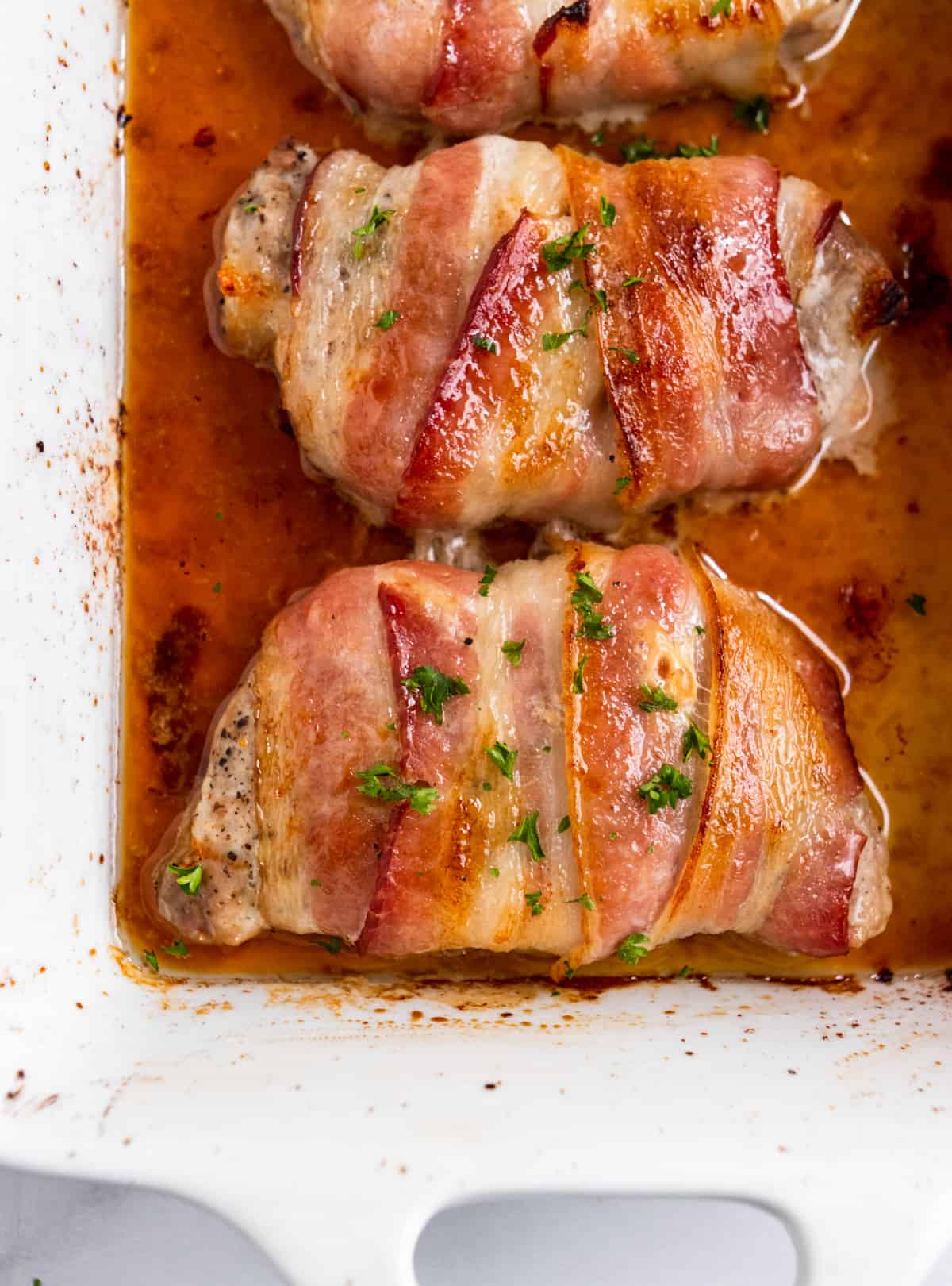 Maple bacon-wrapped pork chops in a white bakingdish.