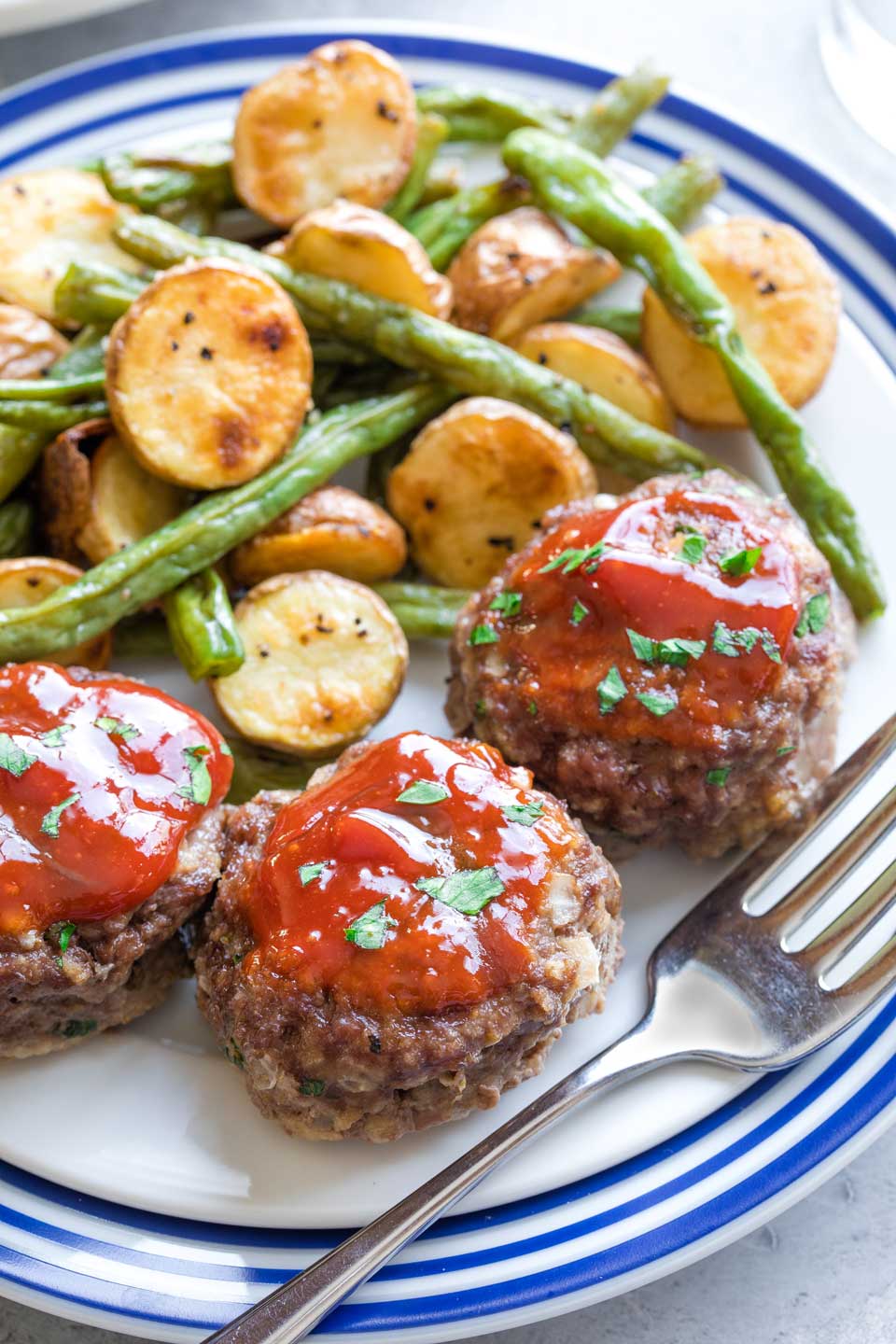 Meatloaf muffins on a blue plate with green beans and potatoes.