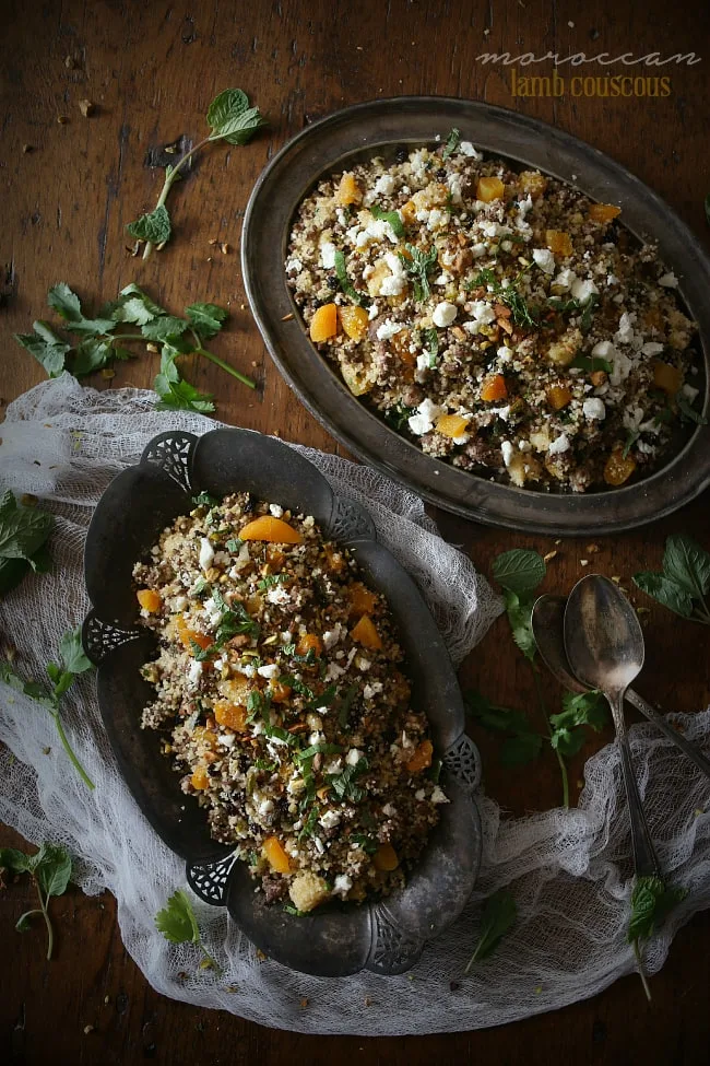 Moroccan lamb couscous with pistachios and apricots on rustic silver serving dishes.
