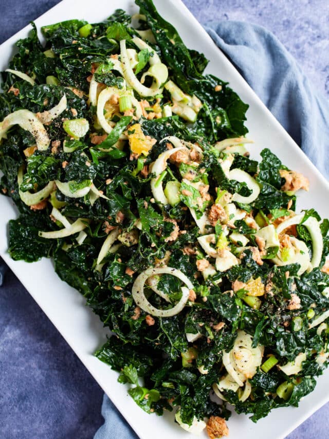 Citrus kale salmon salad on a square plate.