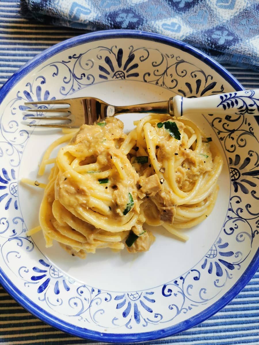 Pasta with tuna carbonara on a decorative plate with decorative fork.