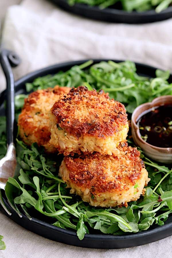 Tuna kimchi cakes with soy ginger dipping sauce on a dark plate.