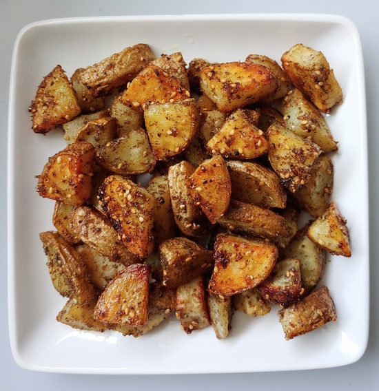 Crispy za'atar roasted potatoes on a white plate.