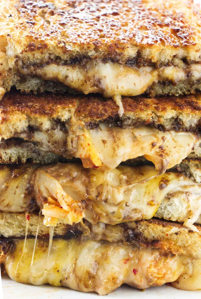 Black garlic kimchi grilled cheese sandwiches cut in half and stacked.