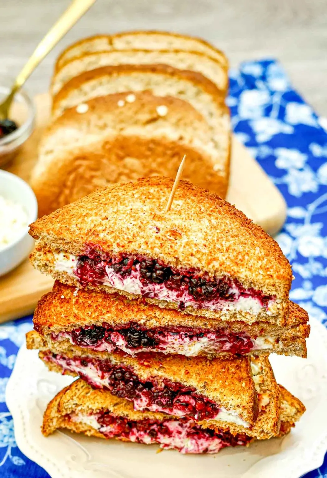 Blackberry goat cheese grilled cheese stacked atop one another on a plate.