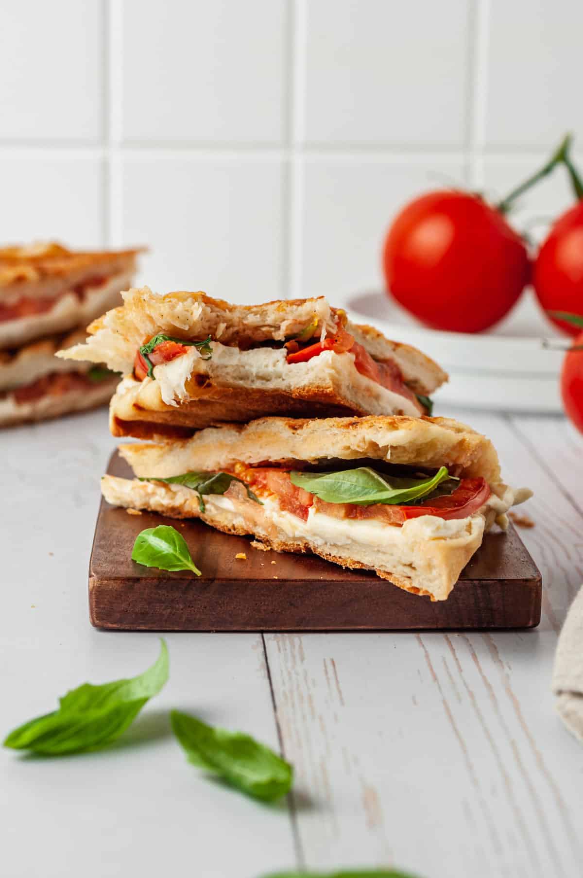 Grilled Caprese panini cut in half on a cutting board.