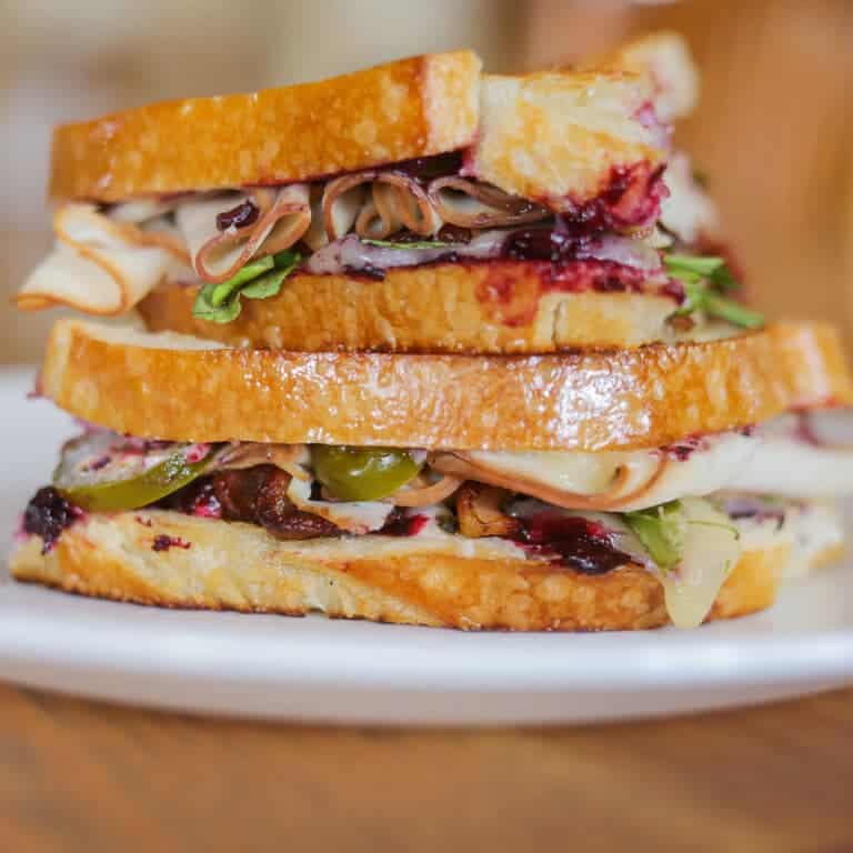 Gourmet turkey bacon grilled cheese sandwich cut in half and stacked on a plate.