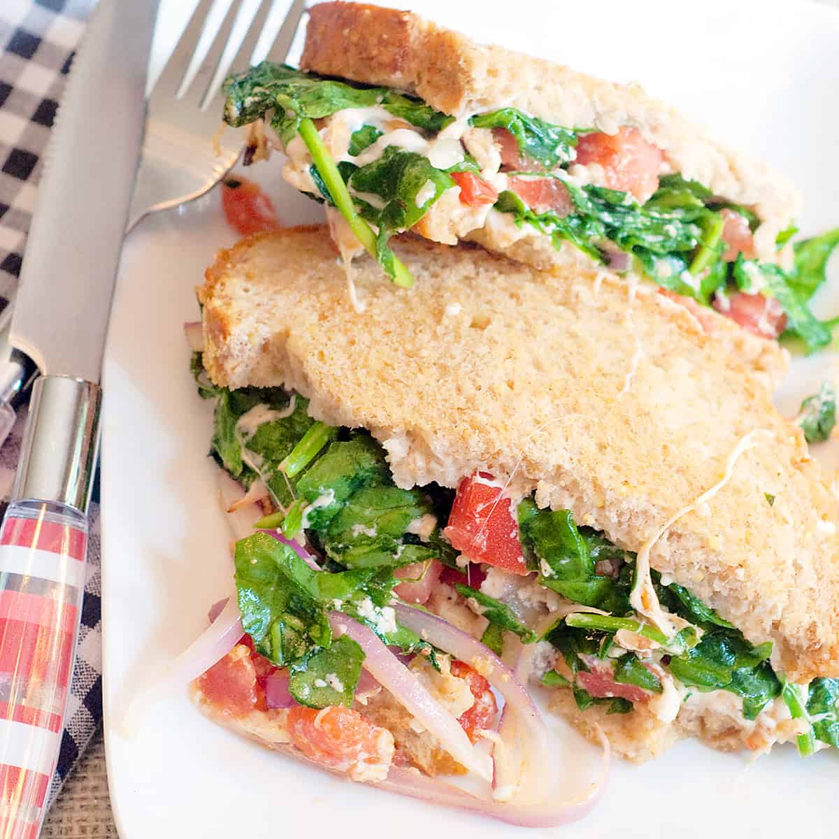 Grilled cheese Florentine sandwich cut in half on a white plate.