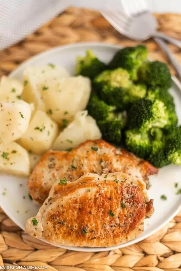 Pork chops, broccoli, and potatoes on a plate.