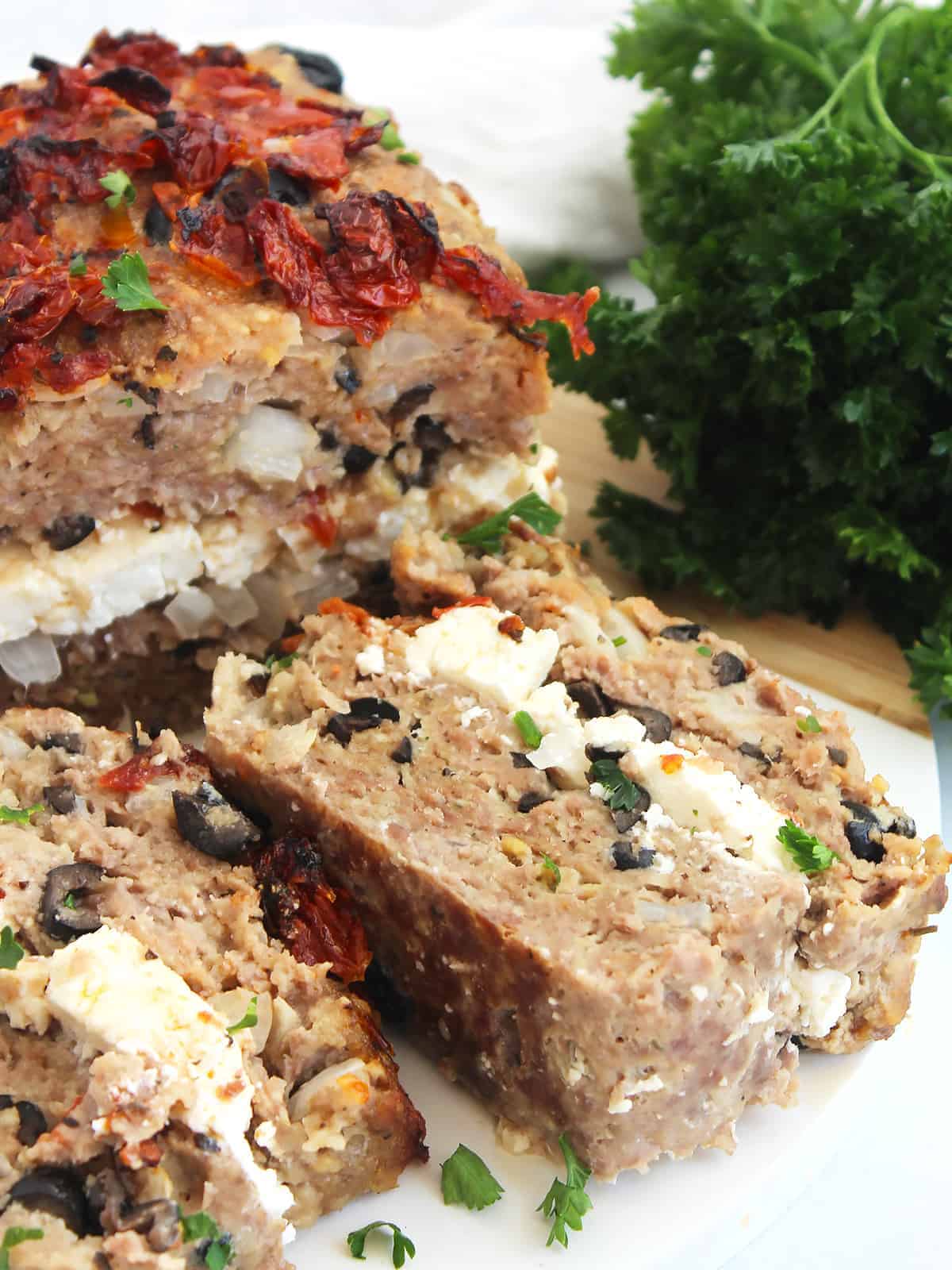 Ground lamb meatloaf with feta and olives on a cutting board.