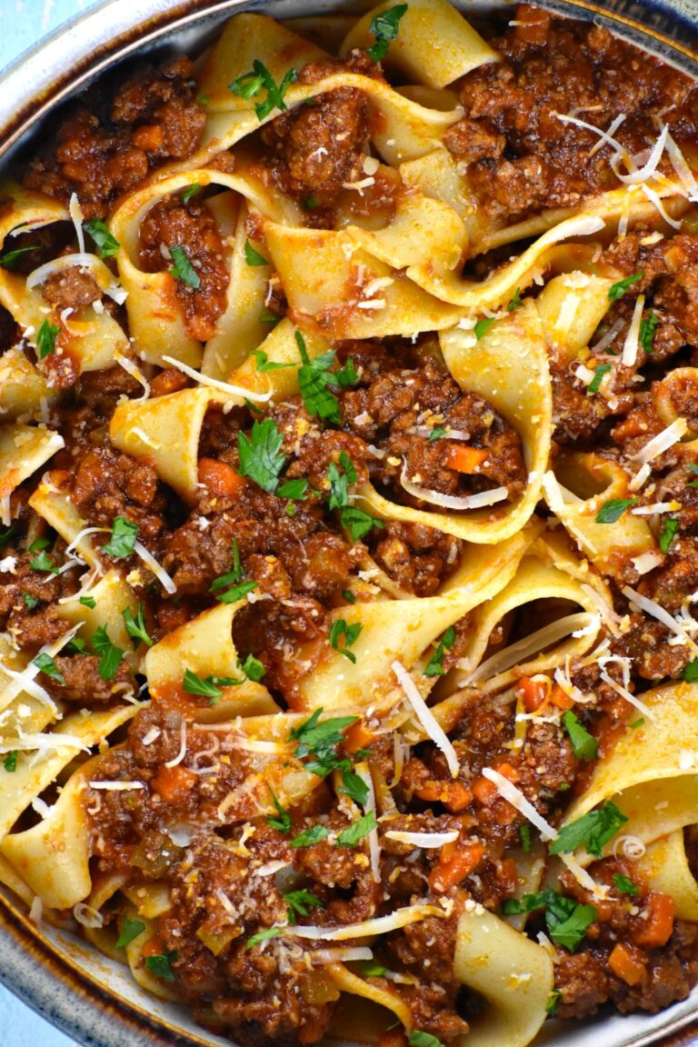  Lamb ragu with pasta and herbs inside a pot.