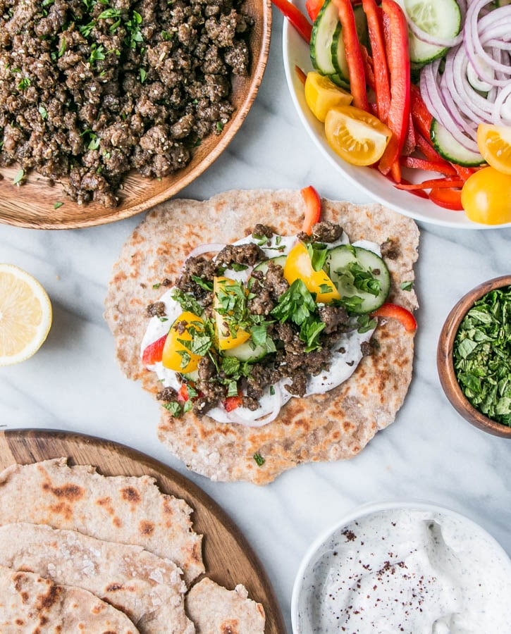 Lamb salad on top of flatbread with more lamb mixture, veggies, and bread.