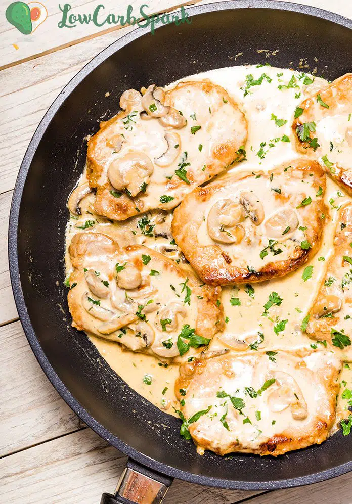 Pork chops in creamy mushroom sauce in a frying pan.