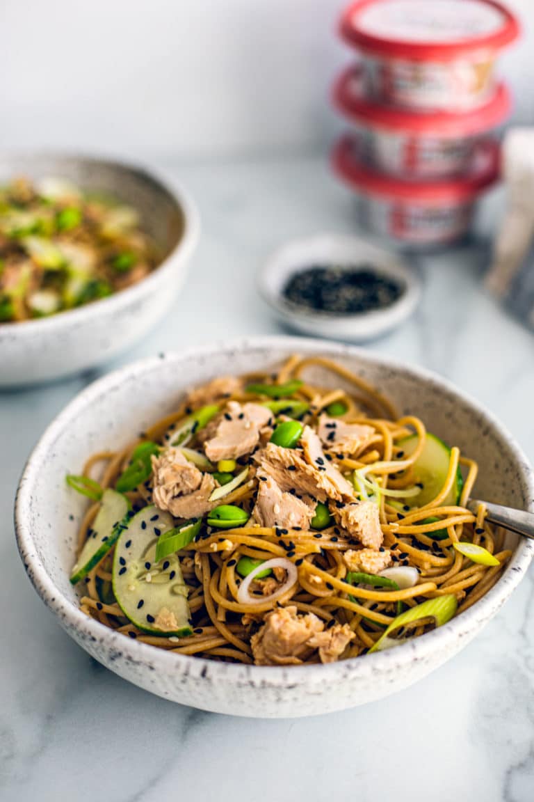 Bowl full of sesame ginger noodles with   pack of salmon.