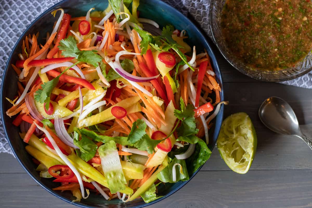 Spicy Thai mango salad in a blue bowl.