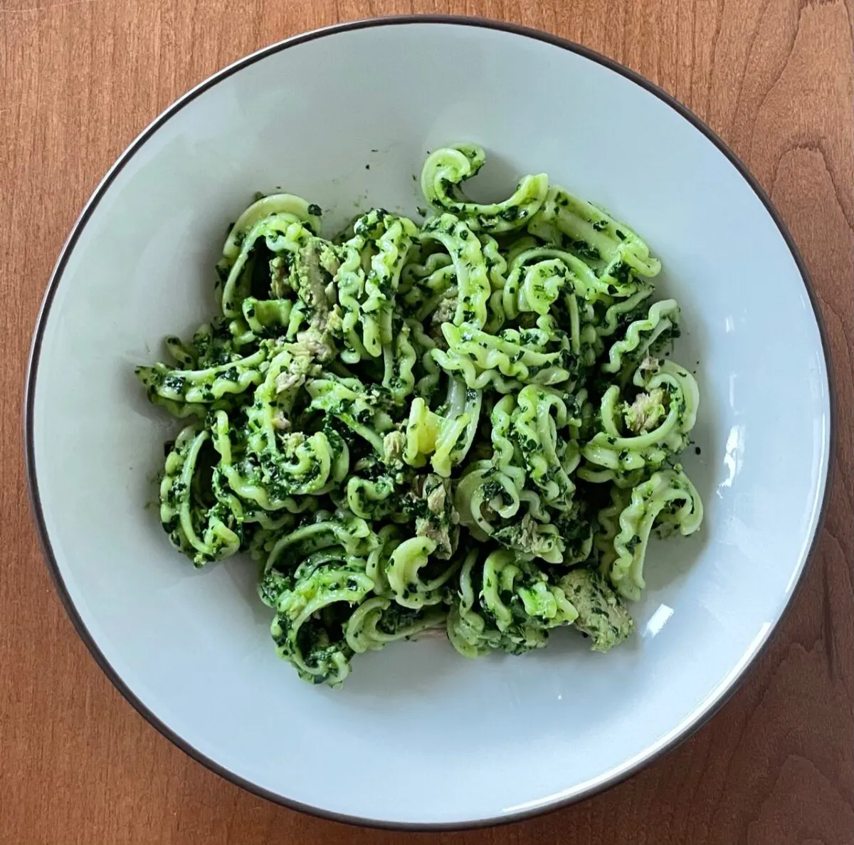 Tuna pesto pasta with arugula spinach pesto on a white plate.