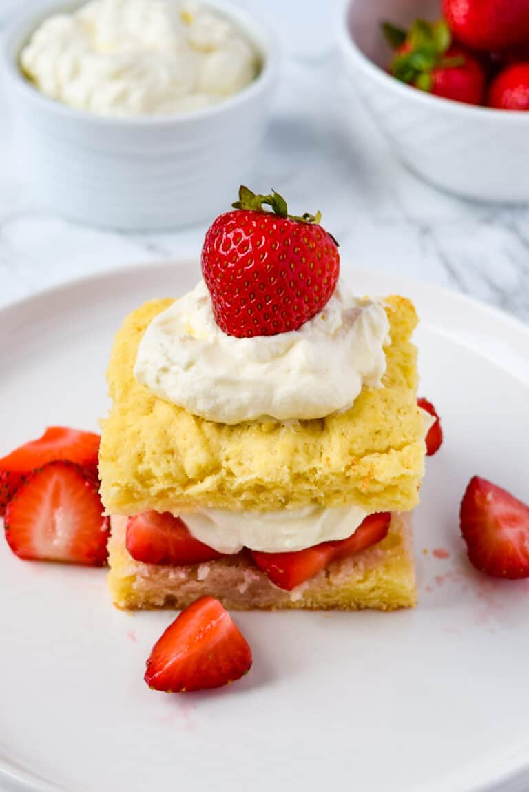 Easy strawberry shortcake with whipped cream and fresh sliced strawberries on a white plate.