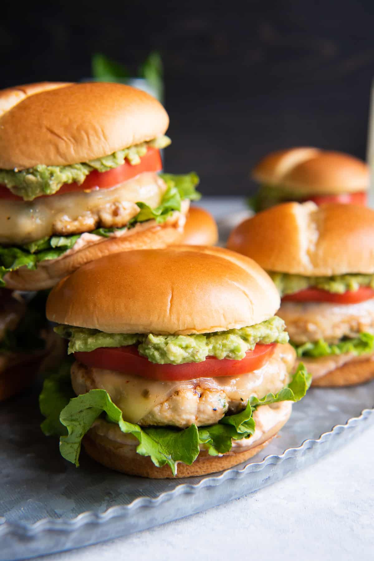 Southwest burger with cheese avocado lettuce and tomato on a bun.