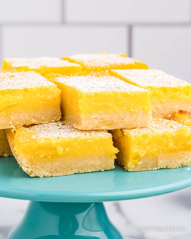 Lemon bars sitting on a dessert stand.