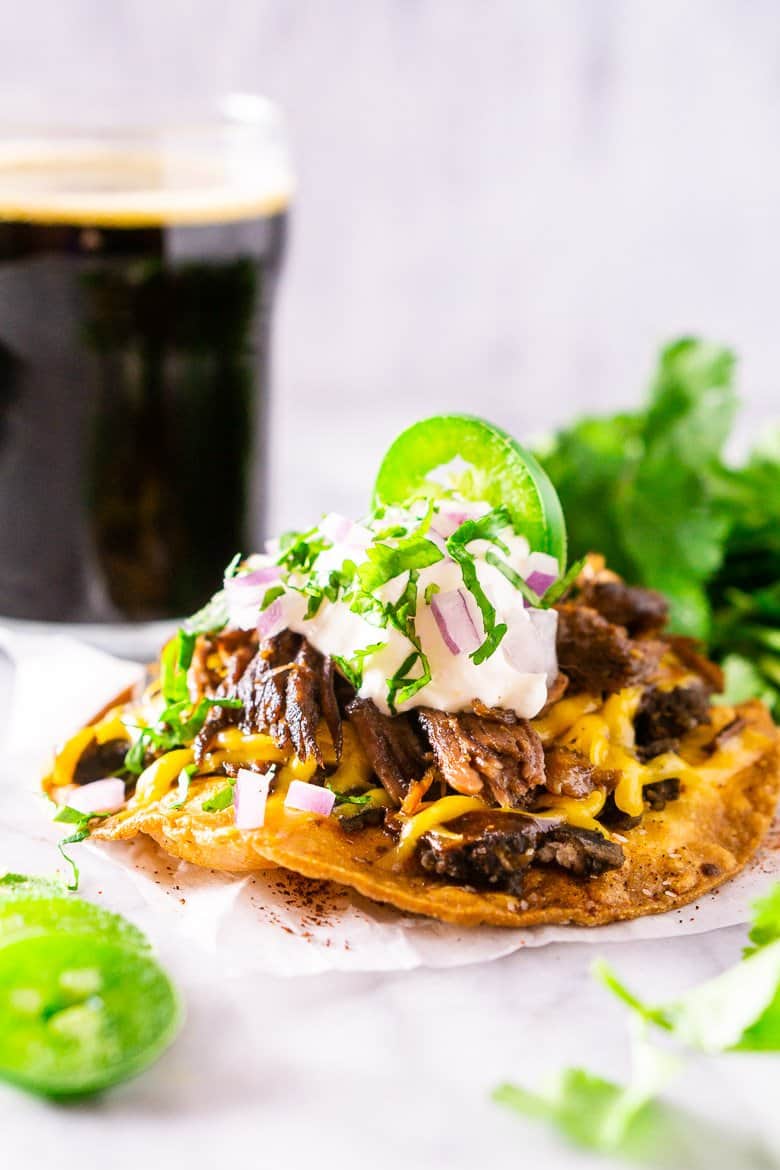 Beer braised Mexican shredded beef tostada with cheese, sour cream, red onion, and jalapeno.