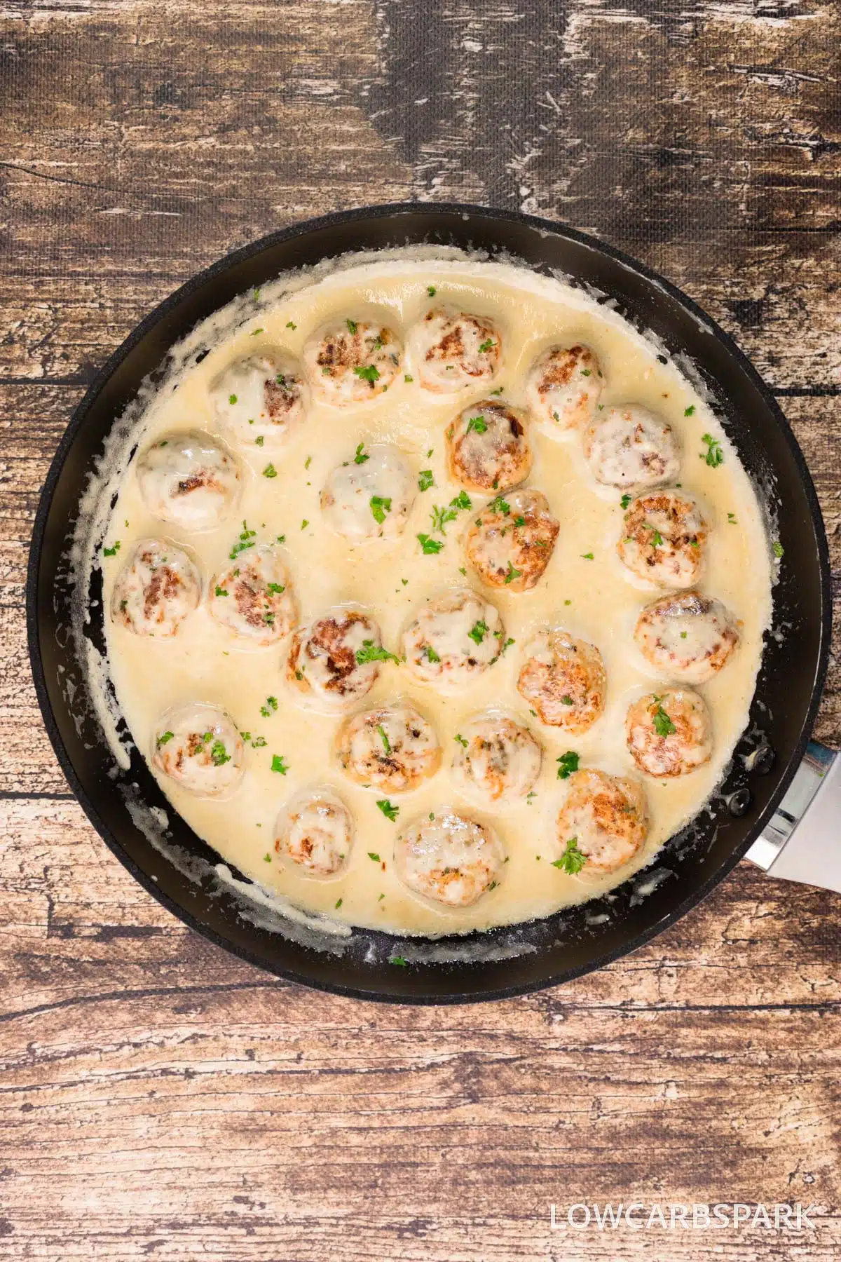 Chicken meatballs in a creamy sauce in a cast iron skillet.