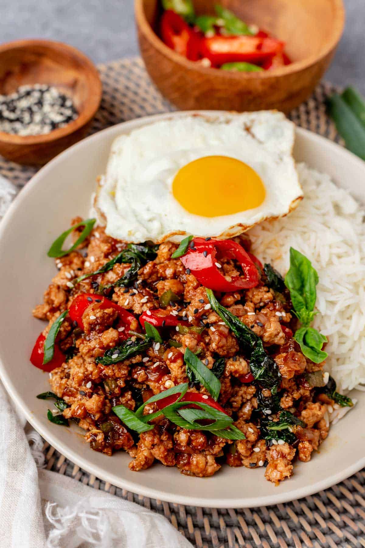 Thai basil chicken with fried egg and rice on a plate.