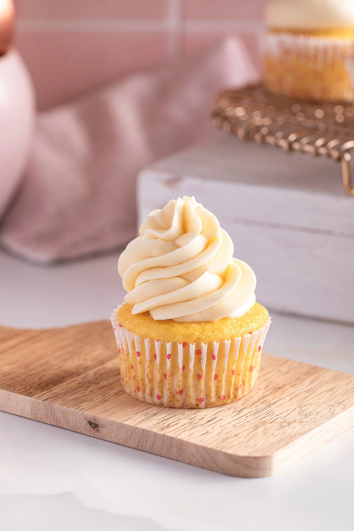 Cupcake with sweetened condensed milk frosting on a wooden board.