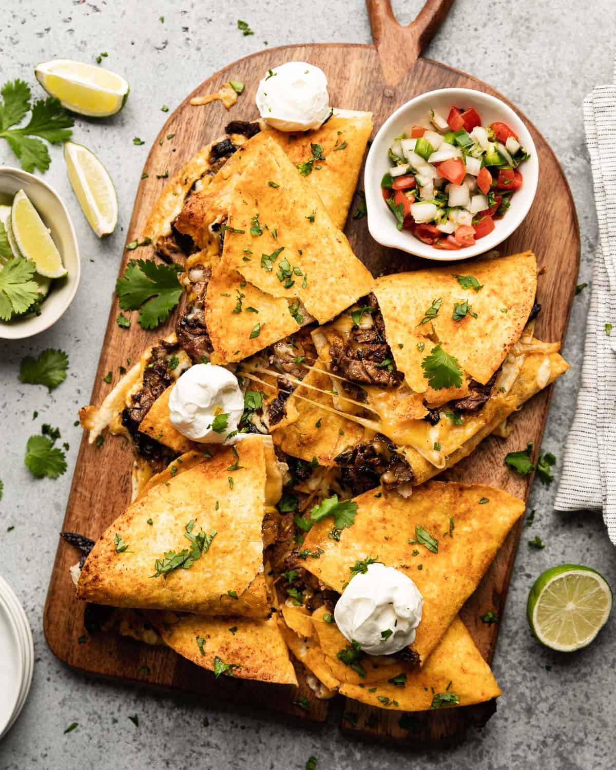 Carne asada quesadillas on a wooden cutting board.