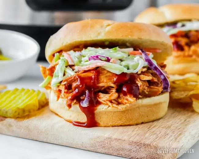 Slow cooker bbq chicken sandwich with cole slaw on a bun.