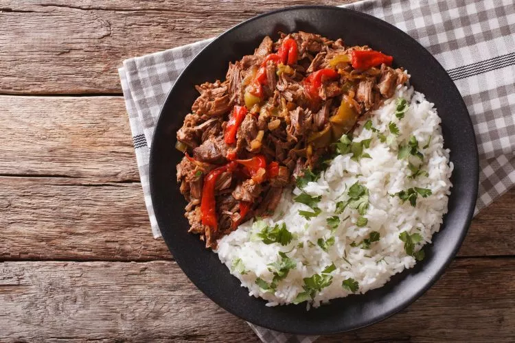 Slow cooker beef machaca with bell peppers, tomatoes, herbs, and spices.