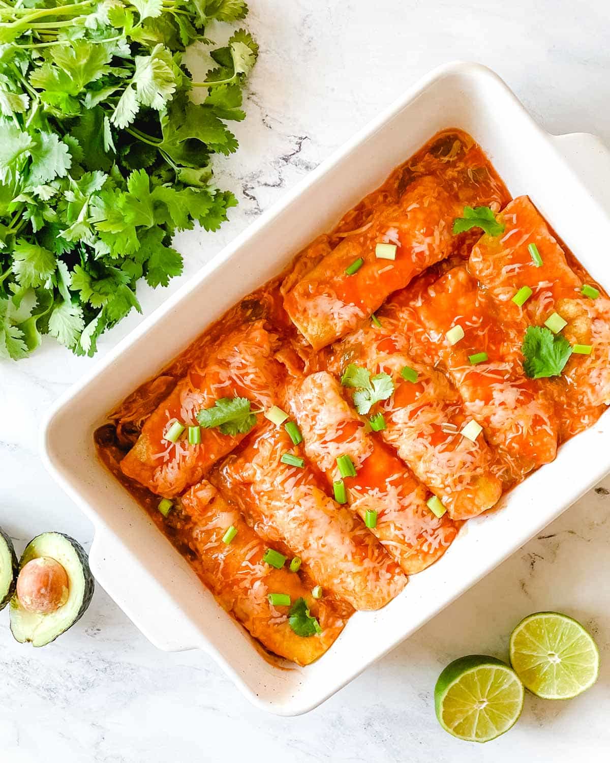 Slow cooker chicken enchiladas in a square baking dish.