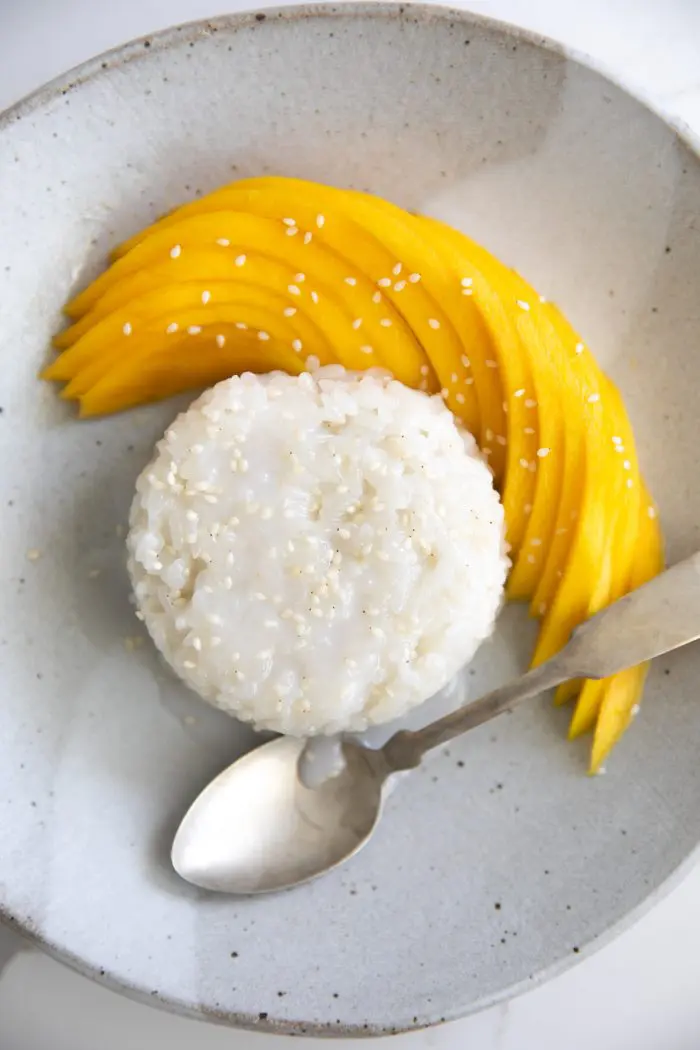 Thai mango sticky rice dessert on a plate with a spoon.