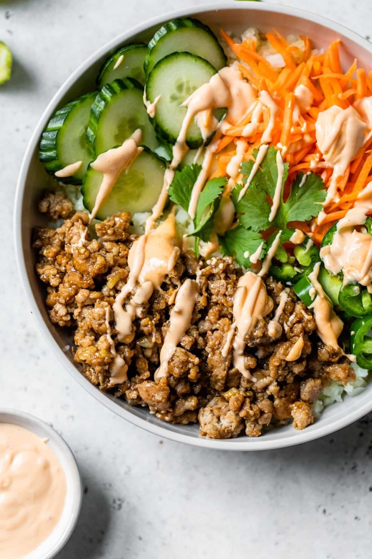 Banh mi bowl with cucumber, carrots, and ground beef in a bowl with sauce.