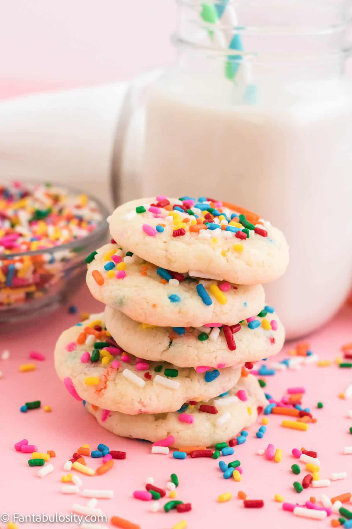 Stack of funfetti cookies and sprinkles scattered around.