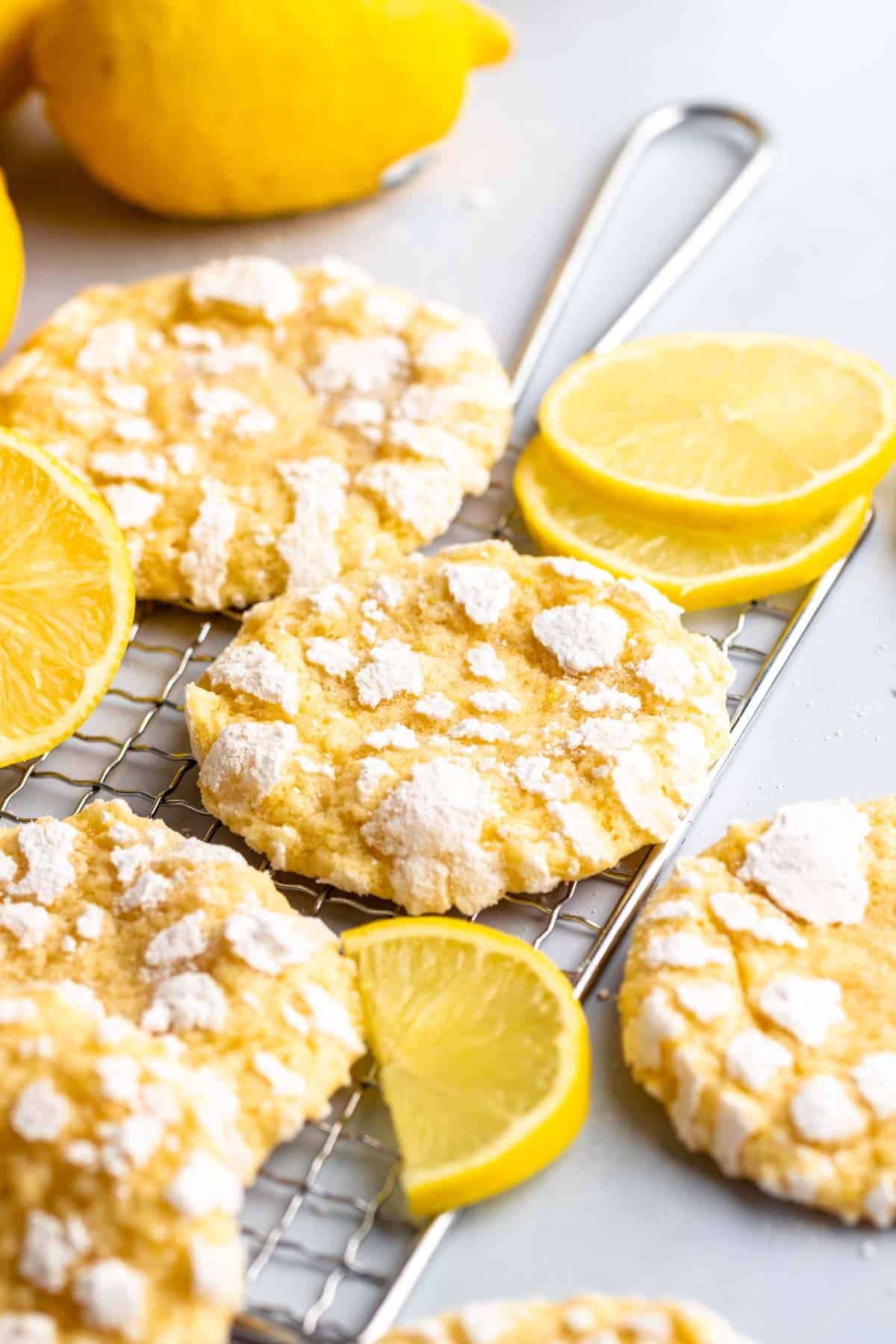 Lemon crinkle cookies on a cooling rack with lemon slices.