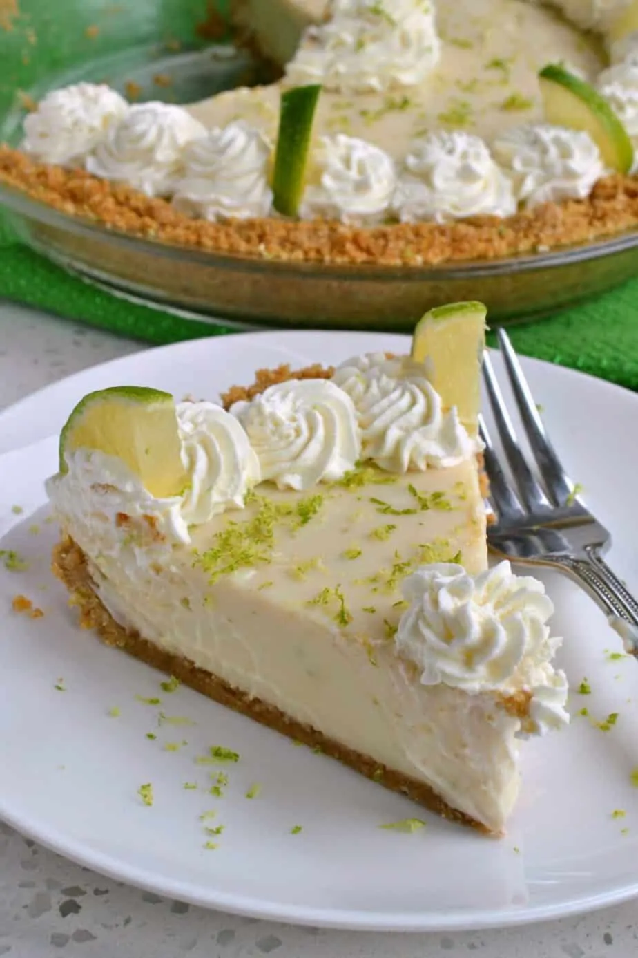 Slice of key lime pie with a fork on a white plate.