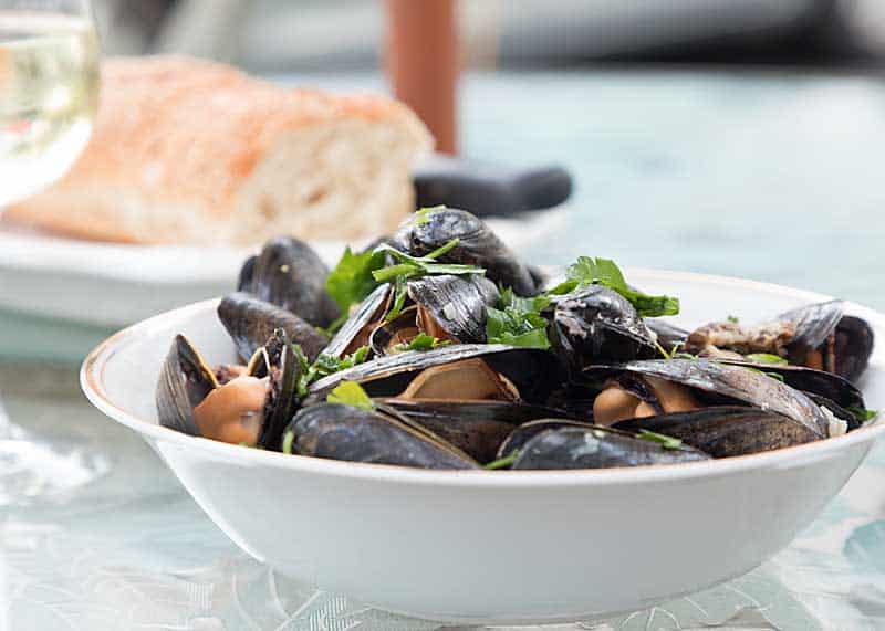 Mussels in mushroom cream sauce in a white bowl.