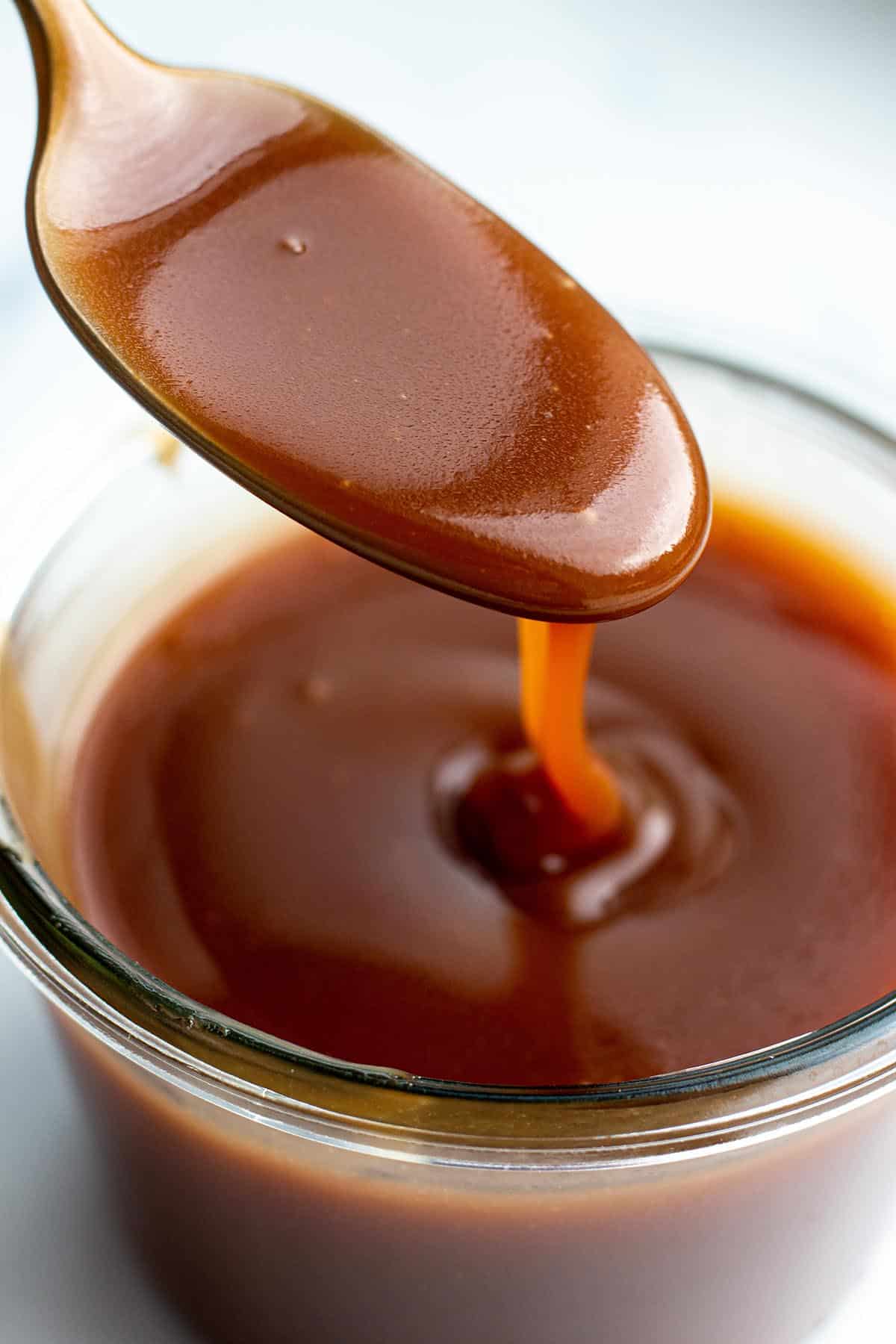 Spoon dripping homemade bourbon caramel sauce. 