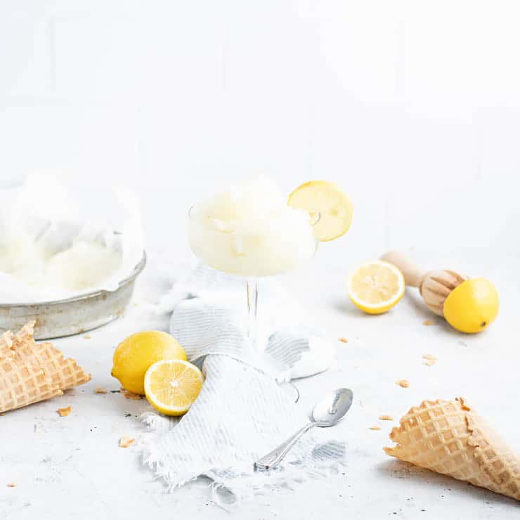 Lemon ginger sorbet in a glass with ingredients surrounding it.