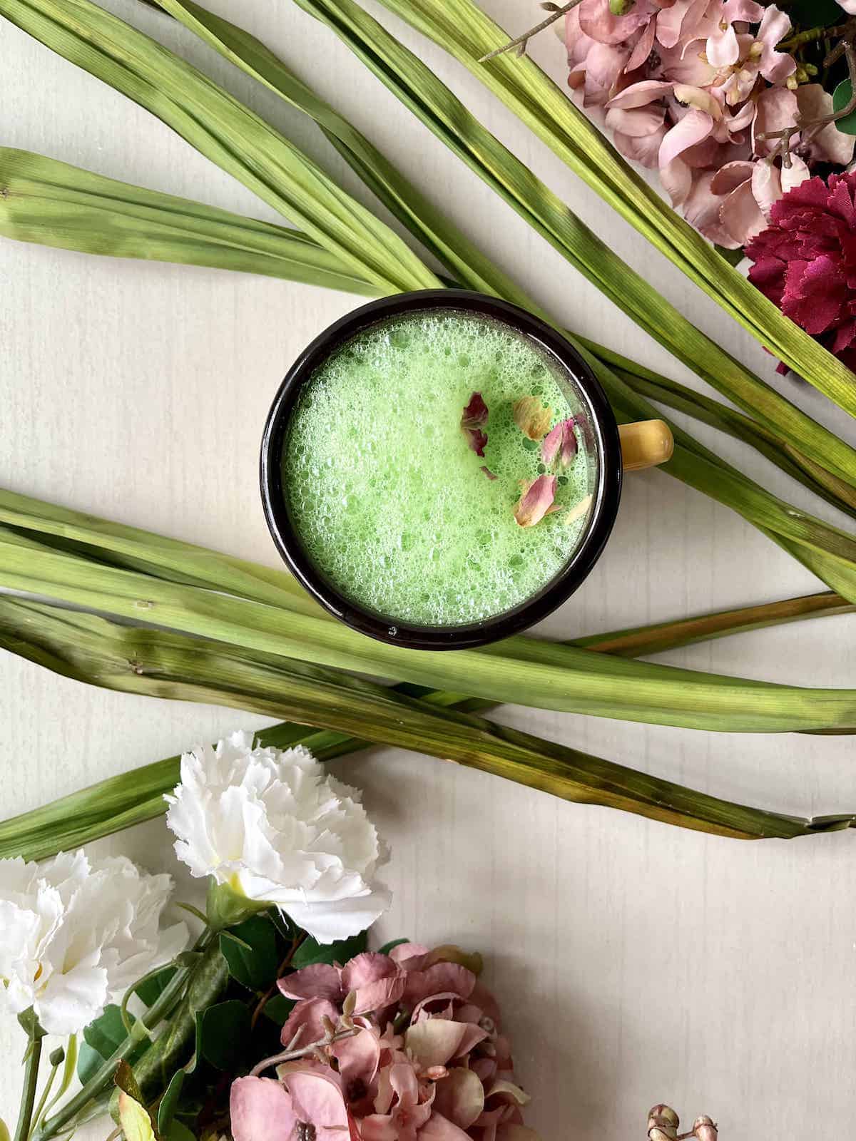 Pandan latte with flowers in the background.