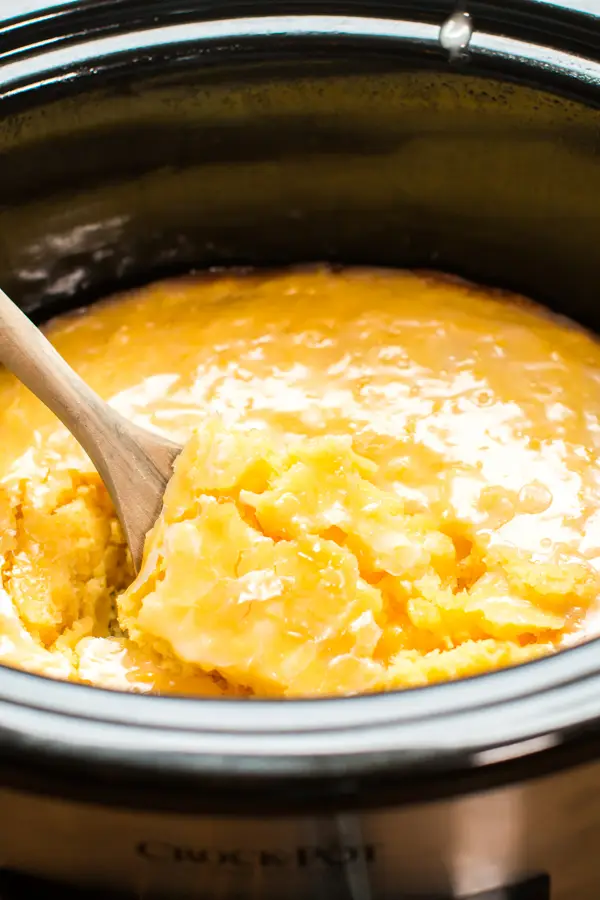 Wooden spoon scooping slow cooker lemon sponge cake.