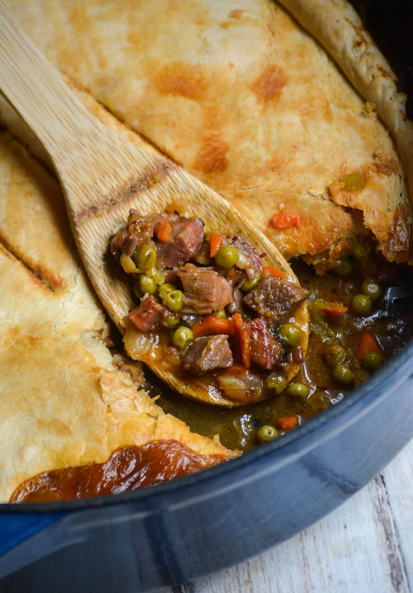 Wooden spoon dipping into brisket cobbler.