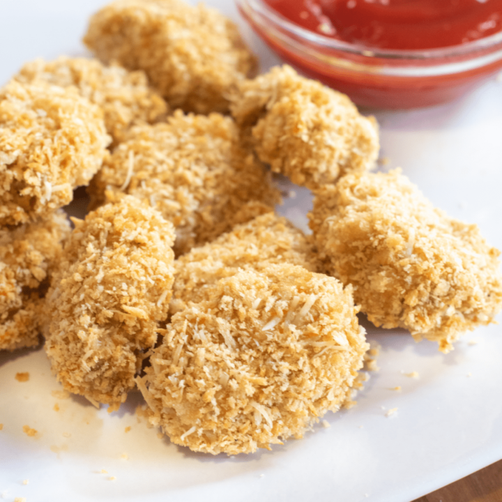 Baked chicken nuggets with ground chicken with ketchup in the background.