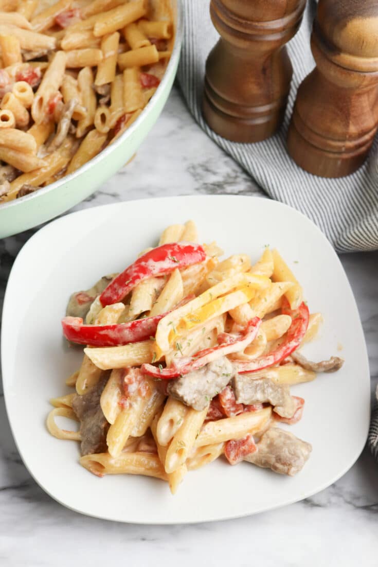 Steak fajita pasta on a white plate.