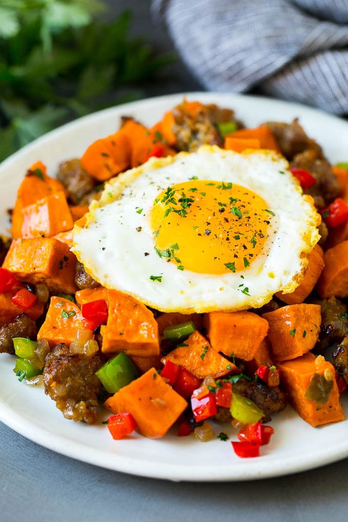 Sweet potato hash with bell peppers, sausage, and a fried egg on top.