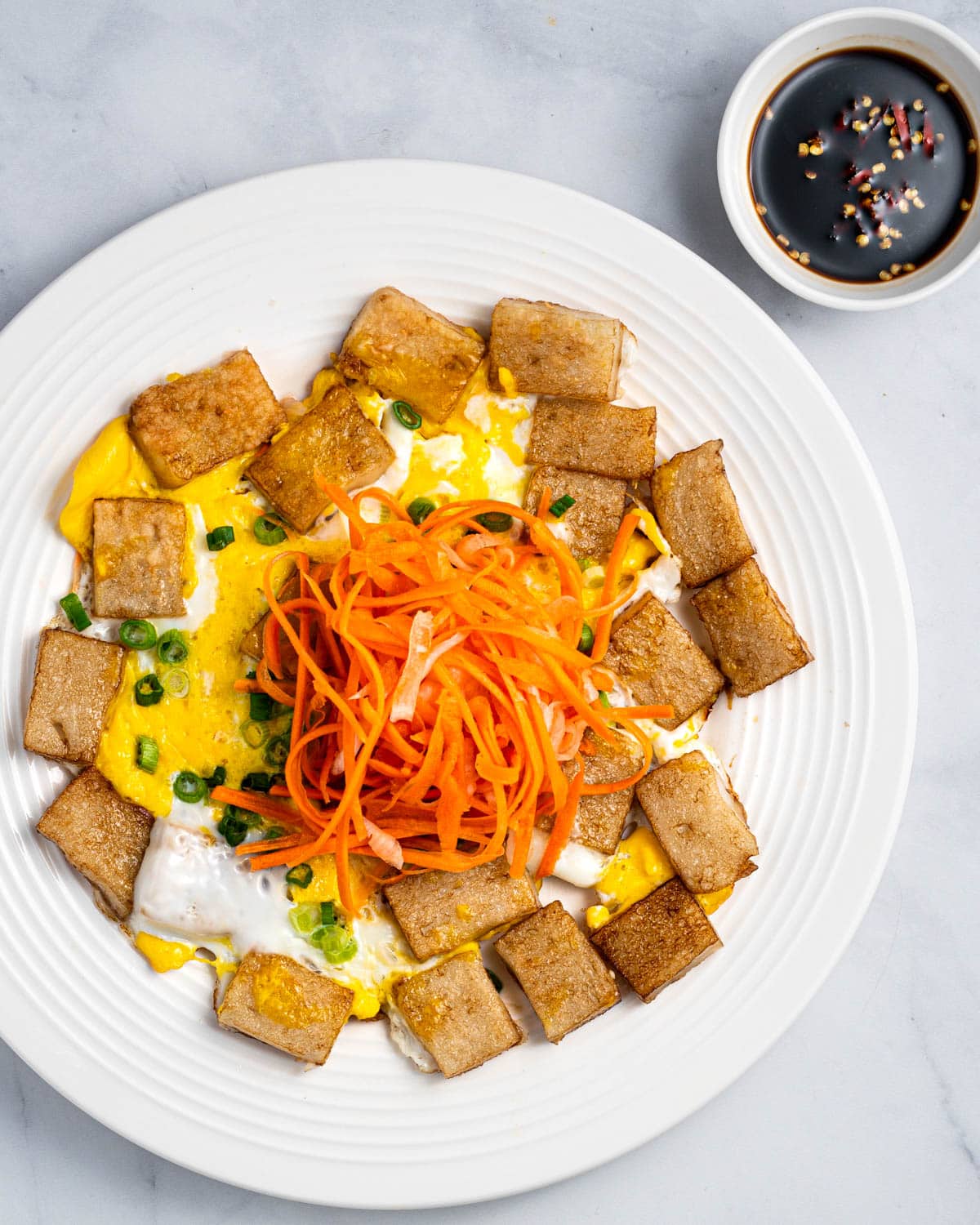 Vietnamese fried rice flour cake on a white plate with sauce in a small bowl.