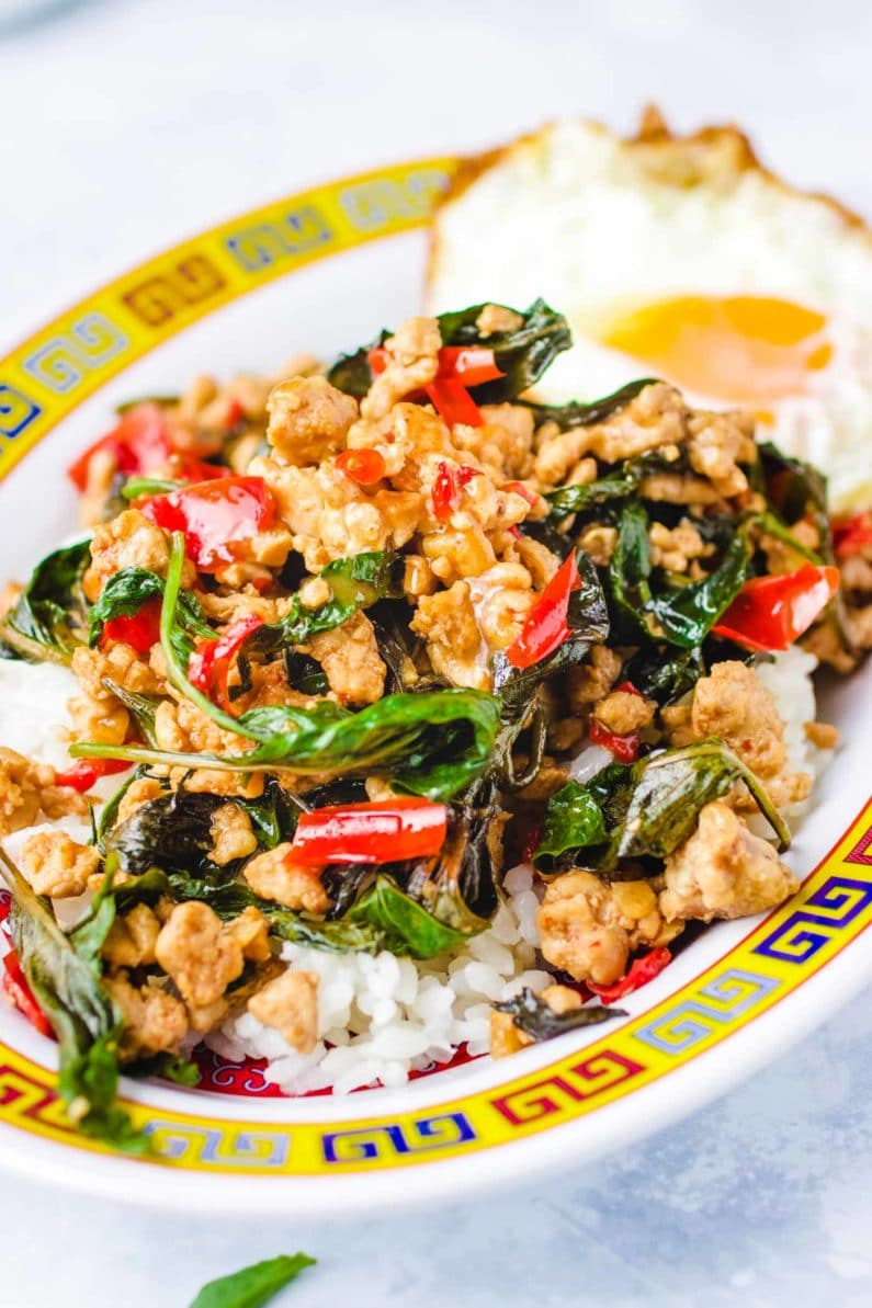 Thai basil chicken on top of white rice on a colorful plate.