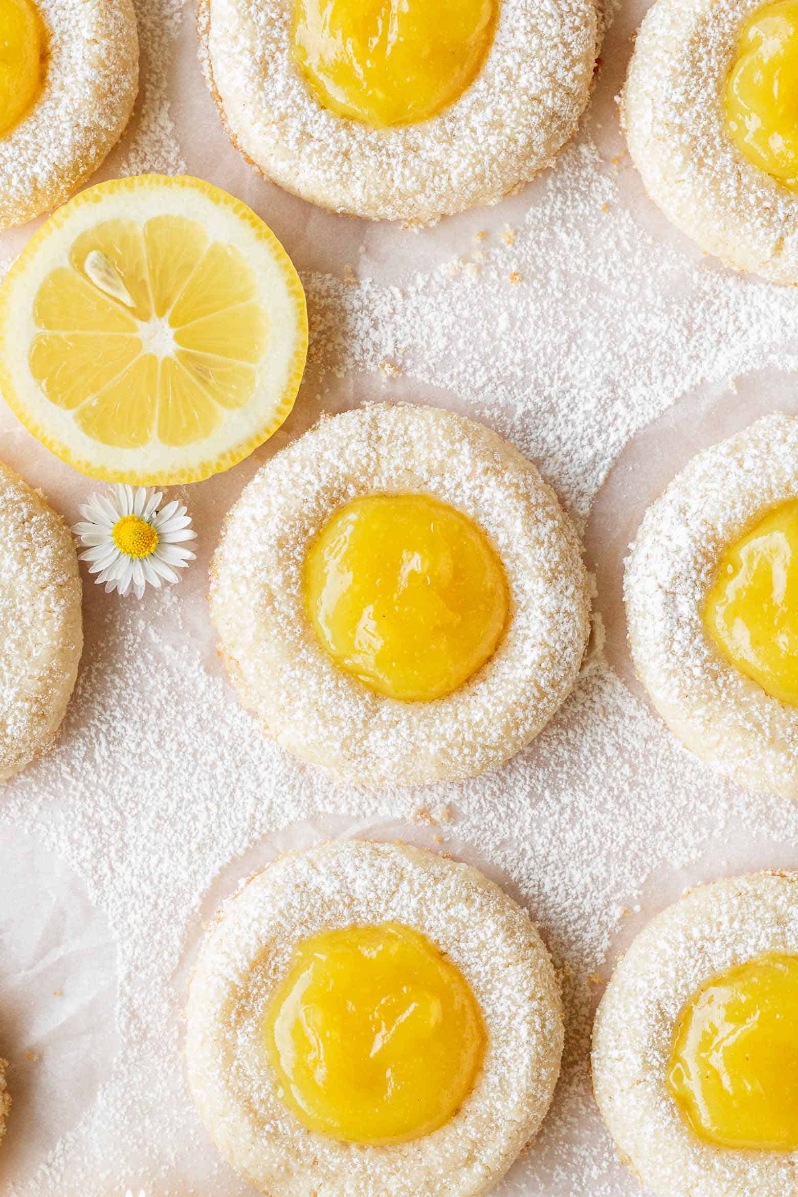 Vegan lemon thumbprint cookies with a slice of lemon and a small flower.