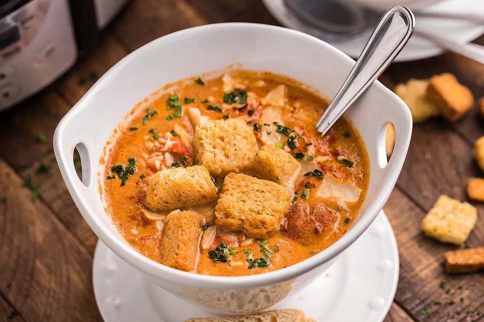 Slow cooker key west crab and lobster bisque in a white bowl with a spoon.